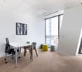 A contemporary meeting room with a white desk, office chairs, blue and yellow stools, and large windows