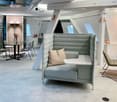 Contemporary design office space with round table, chairs, booth sofa, lamps, and carpet.