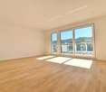Spacious living room with large windows offering a scenic view, hardwood flooring, and an abundance of natural light.