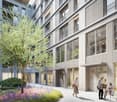 Large modern building, glass windows, multiple floors, green space, small garden area, and trees.