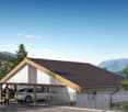 A two-story building with a slanted roof, surrounded by trees and mountains. The building has a covered parking area in the front with space for multiple vehicles.