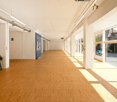 empty room, wooden flooring, bright lighting, long corridor, large windows