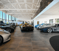 Car showroom, several sports cars parked in the room, wooden flooring, large windows, high ceiling