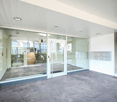 modern entryway with sliding and swinging doors, white ceiling and walls, large windows, mailboxes, grey concrete floor
