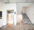 An elevator, a staircase with marble steps, and a marble floor.