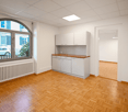 spacious room with wooden parquet floor, white walls, radiator, arched window, built-in cabinets, wooden countertop