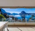 Balcony with table and chairs, glass railings, mountain view, clear blue sky