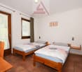 Two twin beds, wooden furniture, tiled floor, large windows with curtains, Assofide S.A. logo on the wall