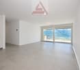large room with a tiled floor, a balcony, and a beautiful view of the sea and mountains