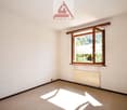 A vacant room with white walls, beige floor, a window, and a radiator.