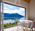 Sliding doors opening to balcony, outdoor dining table with chairs, view of lake and mountains