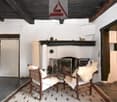 Wooden beams, white walls, tile floor, fireplace, wooden armchairs, rug