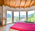 bedroom with large windows and a balcony, wooden ceiling, pink bedspread, white walls, glass mirror