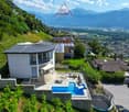 Modern house with a curved roof, swimming pool, solar panels, terrace, located on a hillside