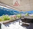 terrace with outdoor seating and table, concrete floor, greenery in white planters, shade, mountain view
