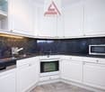 modern kitchen with white cabinetry, black granite countertops, stainless steel sink, built-in oven, microwave, dishwasher, granite flooring