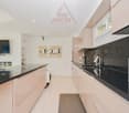 modern kitchen, black countertops, stainless steel appliances, fireplace, tiled floor, wall mounted TV