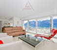 white tiles, glass sliding doors, large windows, beige sofa, two white armchairs, red chair, coffee table, carpet