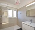 Modern bathroom, shower enclosure, vanity with sink, large mirror, tiled walls and floor