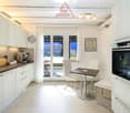 Modern kitchen with a breakfast table and chairs, white cabinets, brown countertop, glass doors to the balcony with a view