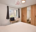 bedroom with a double bed, desk with laptop, curtains, wardrobe, view to the outside