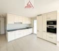 modern kitchen with white cabinets, black countertops, stainless steel appliances, tiled floor