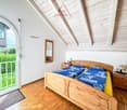 wooden bed, blue sheets, wooden nightstands, lamps, mirror, wooden ceiling, glass door, wooden floor, view of the outside