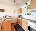 kitchen with dining area, wooden cabinets, white countertops, sink, stove, oven, refrigerator, picture frame, couch, rug
