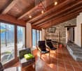 wooden ceiling, stone wall, large windows, chairs, table, fireplace, view of the outside