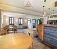 Wooden tables and chairs, wooden counter, stone wall, plants, lamps