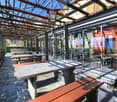Outdoor seating area with stone benches, wooden pergola, glass walls, and a view of the surrounding area.