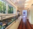 modern kitchen with granite countertops, stainless steel sink, dishwasher, large windows, wooden floor