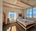 bedroom with bed, wooden chair, wooden cabinet, rug, picture frame, windows with curtains