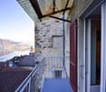 Balcony with metal railing, red shutters, view of mountains and lake