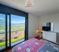 bedroom with large windows, balcony, TV, lamp, dresser, mirror