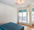 bedroom with double bed, sliding glass door to balcony, wooden floor, white walls, ceiling light