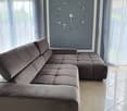 L-shaped sofa, gray walls, large clock, white curtains, tiled floor