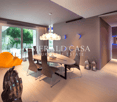 Spacious dining area with large windows overlooking a garden, modern dining table and chairs, pendant lighting fixture, and decorative accents.