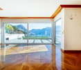 Large room with wooden floor, glass sliding doors, balcony view, large windows