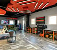 Wooden floor, red hanging lights, monitors, desk, cabinets, storage boxes, plant, tools, equipment, treadmill, windows