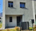 2-story building, white walls, large windows, gray shutters, garden, gate, gray mailbox, gravel driveway
