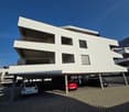 White residential building with multiple balconies and covered parking area