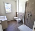 modern shower stall, toilet, bidet, sink, tile flooring, window with a view