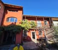 red painted exterior, 3 story, wooden balcony, double doors, arched windows, garden, patio table