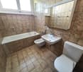 Bathroom with bathtub, toilet, sink, and mirror with floral tiles