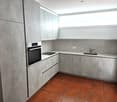 modern kitchen with gray cabinets, red tiled floor, built-in oven, sink, faucet, window