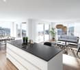 dining table, chairs, couches, kitchen island, stove, white cabinets, pendant lights, windows, balcony, mountain view