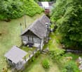 stone and wood exterior, steep surroundings, roof covered with rocks, fenced garden