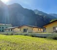 Houses with mountain view, different colors, fence, concrete barrier, car parked in front of one of the houses