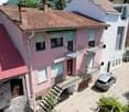 two story building, red roofs, windows with shutters, stairs leading to entrance, balconies, parked cars